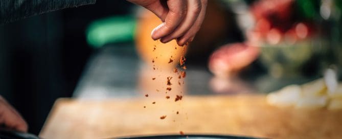 Sprinkling Ground Red Chili Pepper Paprika over Sliced Vegetables